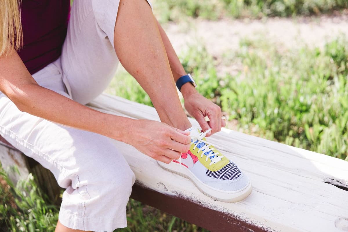 Stephanie lacing up her walking shoes on a sunlit bench, ready to step up