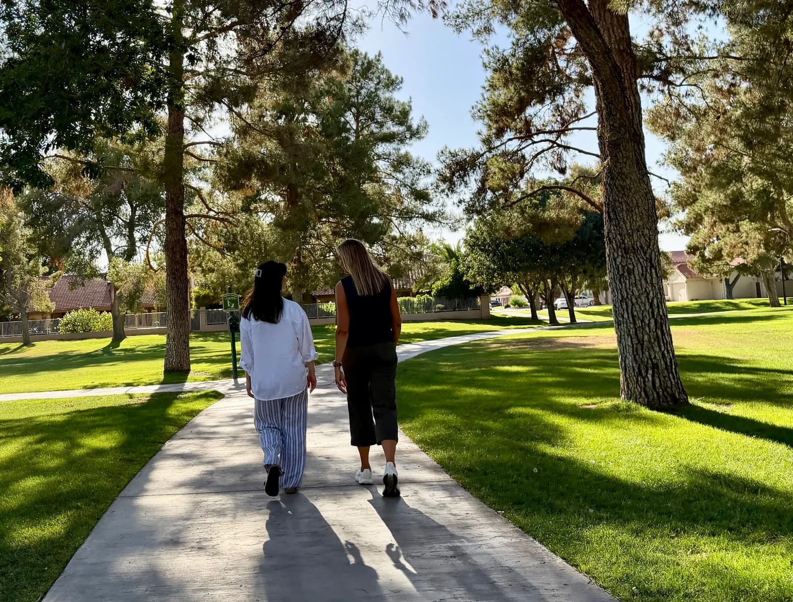 Stephanie Schmid walking with a client on a sunlit park path